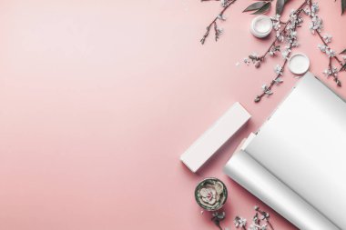 Cilt bakım ürünlerini taklit eden boş çarşafları olan, mercan arka planda sulu bitki ve bahar çiçekleri olan, fotokopi alanı olan bir dergi. Güzellik blogu düzeni. Pastel renk. Düz yatıyordu.
