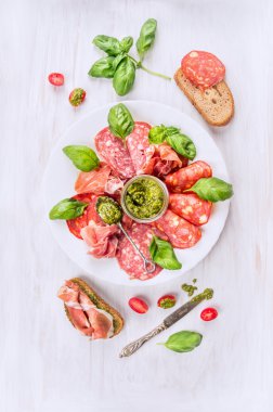 İtalyan soğuk et tabağı ile ekmek, fesleğen pesto ve domates, üstten görünüm