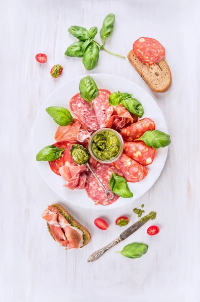 Plato de carne fría italiana con pan, pesto de albahaca y tomates, vista superior — Foto de Stock