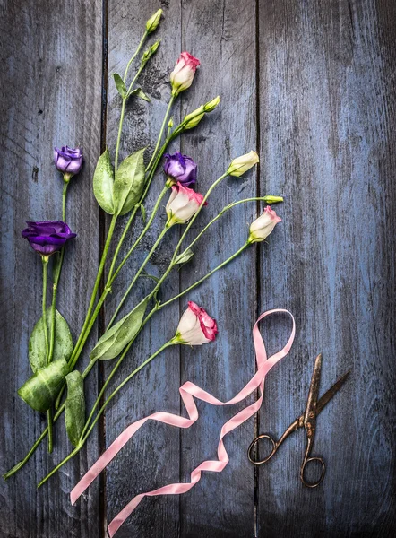 Lato kwiatów ze wstążki i nożyczki na niebieski drewniany stół, widok z góry — Zdjęcie stockowe