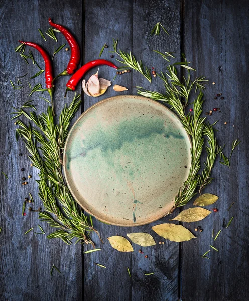 Βότανα και μπαχαρικά γύρω από το άδειο platte σε σκούρο μπλε φόντο ξύλινη, κάτοψη, τοποθετήστε για κείμενο — Φωτογραφία Αρχείου