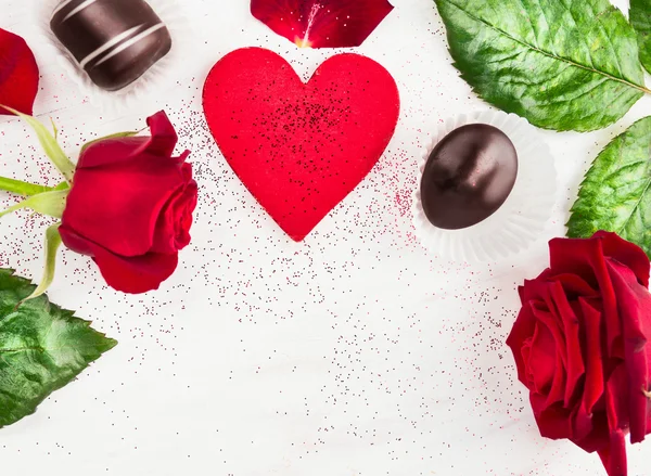 Amor corazón fondo con rosas rojas y pralinés de chocolate, San Valentín —  Fotos de Stock