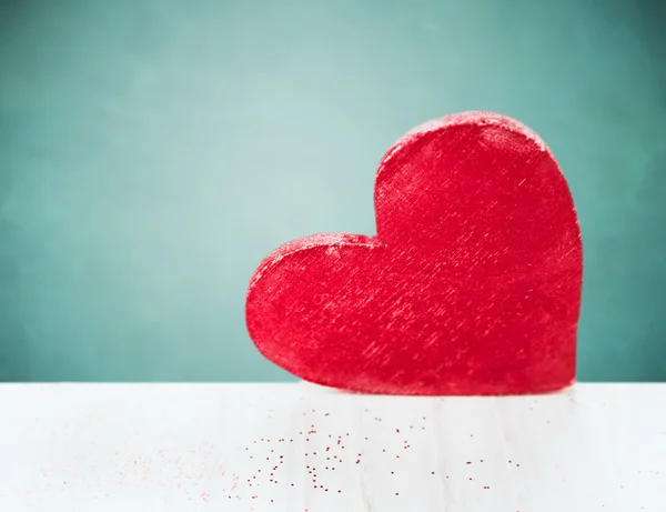 Big red heart on white wooden table over  blue background — Stock Photo, Image