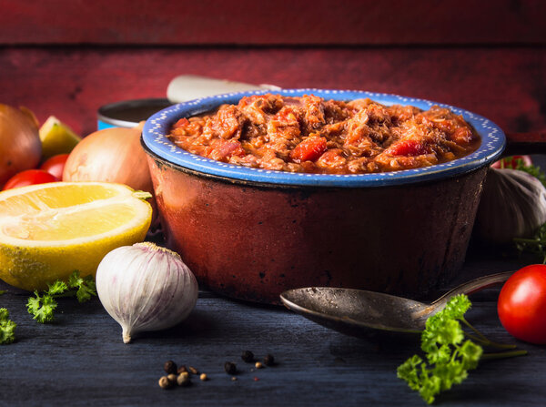 Tomato sauce with tuna fish in old pot with spoon and spices