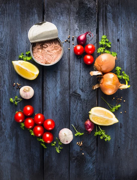 ingredients for tomato sauce with tuna fish: herb, spices and lemon on blue wooden background, frame, top view