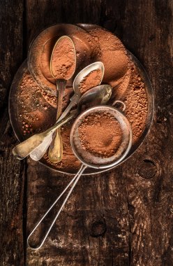 Çikolata tozu kaşık ve koyu ahşap zemin, üstten görünüm üzerine süzgeç ile