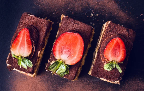 Chocolade tiramisu cake met aardbeien op zwarte leisteen, bovenaanzicht — Stockfoto