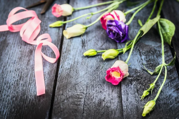 Flowers with ribbon on table — Stock Photo, Image