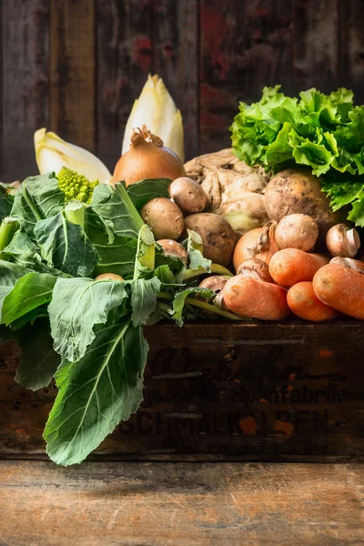 Organic vegetables box on old wooden background — Stock Photo, Image