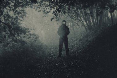 Huysuz, sisli sonbahar ormanlarında parlayan gözleri olan korkunç bir kukuletalı figür. Bir grunge, bulanık, desenli düzenleme ile