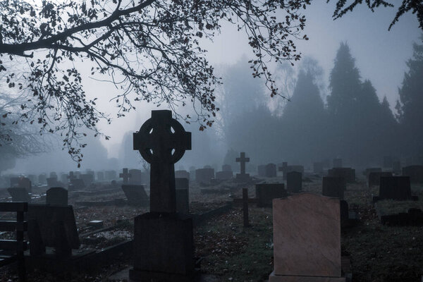 A spooky Victorian graveyard on a foggy, winters night