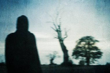 Kırsal kesimde ürkütücü bir kış gününde tarladaki bir ağaca bakan bir adam. Bir grunge, sanatsal düzenleme ile.