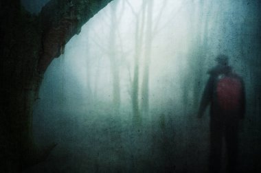 Dengesiz, sisli bir kış gününde, ürkütücü bir ormanda sırt çantasıyla gezen bir yürüyüşçü konsepti. Bir grunge, soyut düzenleme ile.
