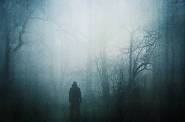 Huysuz ve sisli bir kış gününde ürkütücü bir ormanda bir figür. Bir grunge, soyut düzenleme ile.