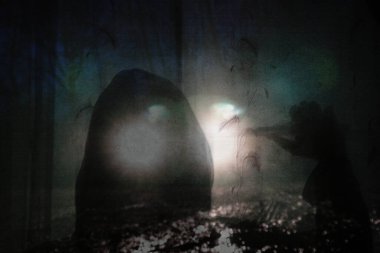 Gerilim konsepti. Kapüşonlu bir figür, kameraya doğru. Pencereden dışarı bakmak, izole edilmiş hissetmek. Arabanın farları üstte katmanlı. Huysuz, grunge, düzenle.     