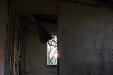 Terk edilmiş, ürkütücü bir evde gün batımında pencereden dışarı bakıyorum. Çürüyen duvarlar ve çatıyla.             