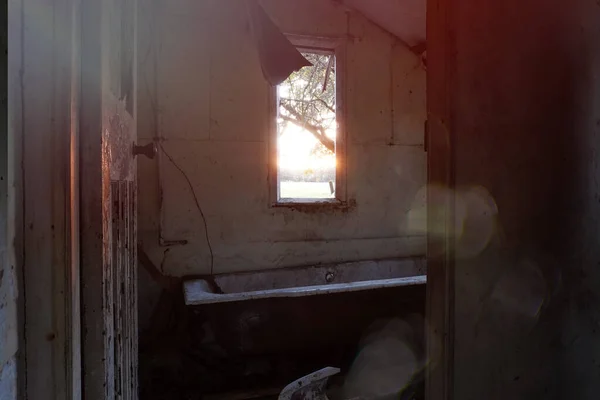 Looking out of a window at sunset in a spooky abandoned house. With decaying walls and broken bath. With a retro, light leaks edit.