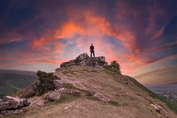 一个男人 背对着站在山顶上看着美丽的落日的相机 — 图库照片