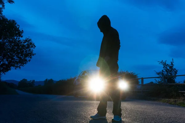 謎のフードの男 バックカメラに 長い直線道路を見て バック車のヘッドライトで点灯 夏の夜に イギリス — ストック写真