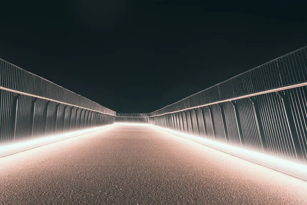 Boş, modern bir yaya köprüsü, bir yaz gecesinde parlayan ışıklarla aydınlanıyor..
