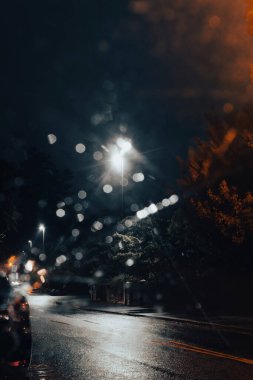 Gece karamsar bir yolda arabanın camından bakmak. Sokak lambaları bokeh etkisi yaratıyor.. 