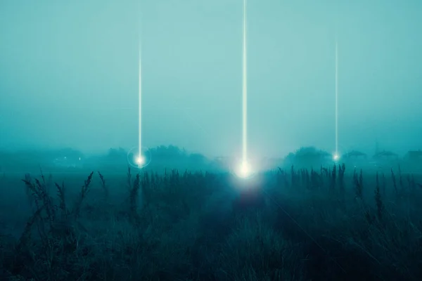 A moody science fiction concept, of UFO light beams landing in a field coming down from the sky. On a foggy spooky night.
