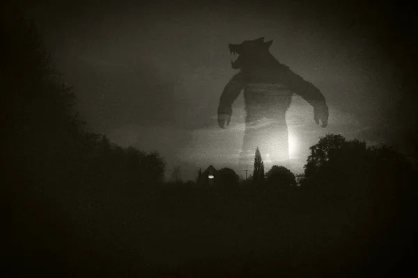 一个可怕的概念一个巨大的狼人在夜晚站在房子和乡间之上带着闷闷不乐的纹理编辑 — 图库照片