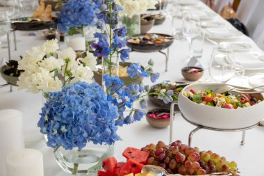 Düğün süsleri. Dekoratif taze çiçekler ve kurumuş çiçeklerle servis edilen düğün masası. Kutlama detayları. Çiçek kompozisyonu gül tabakları ve şamdanlardaki mumlar