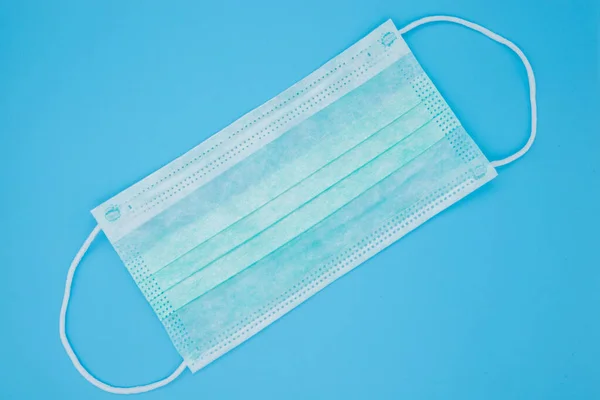 Surgical mask with rubber ear straps. Typical 3-ply surgical mask to cover the mouth and nose. Procedure mask from bacteria. Protection concept.