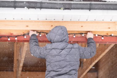 Genç adam Noel ışıklarıyla evi dekore ediyor.