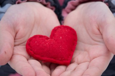 Kadın elleri dışarıda kırmızı el yapımı kalp veriyor.