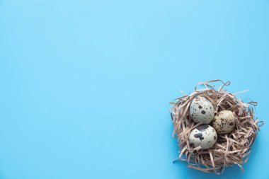 Mavi Paskalya yumurtaları ve kır masa odununda bir buket çiçek.