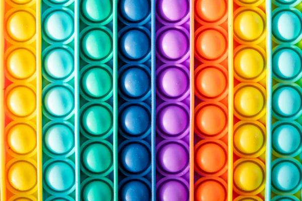 Renkli arka planda çocuklar ve yetişkinler için parlak gökkuşağı oyuncağı antistresi.