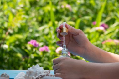 Yapraktan şişeye yağ damlıyor. Esans sıvı kozmetik. Parfüm. Romaterapi. Beyazda izole edilmiş.