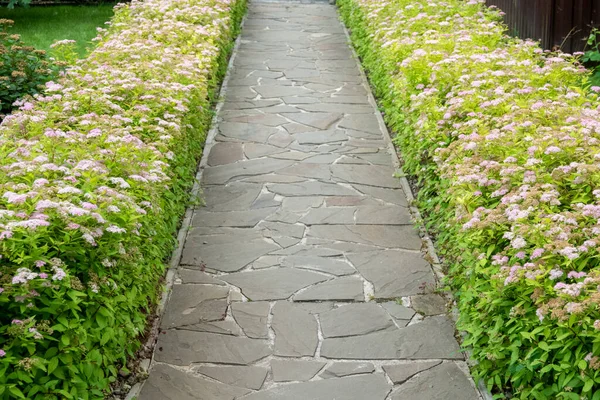 There is a black stone garden on the edge of the curved path, and the landscape lamp is on the green lawn. — Stock Photo, Image