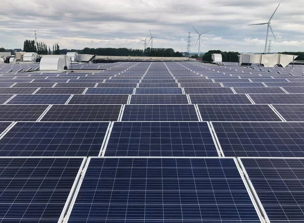 Arka planda rüzgar türbinleri olan çatıdaki güneş panelleri.