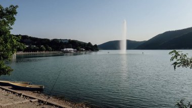 ABRAU-DYURSO, RUSSIA - CIRCA SEPTEMBER 2020: Rusya 'nın güney kıyısında güneşli bir günde suni çeşmeyle dağlardaki Abrau Gölü manzarası.