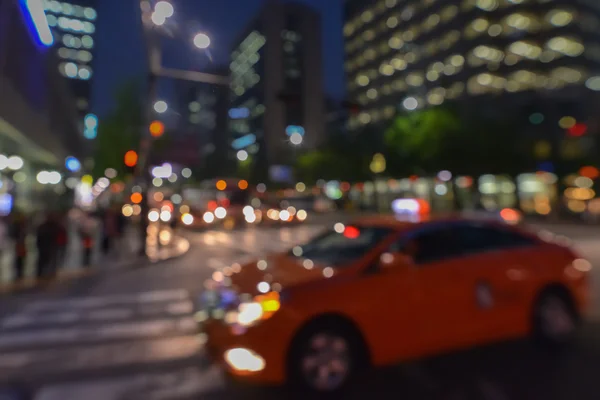 Prachtig wazig nacht stadslichten en de oranje auto — Stockfoto