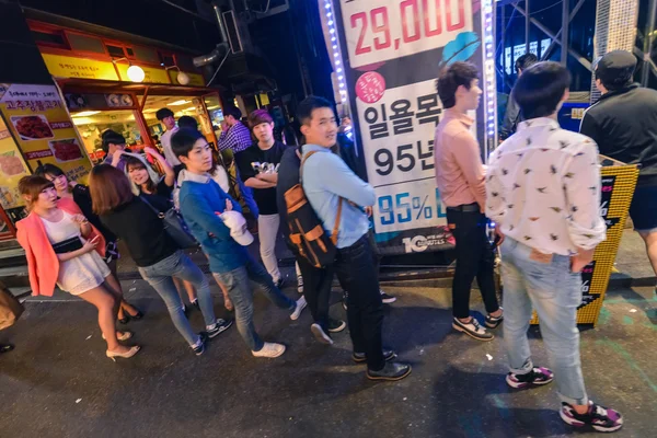 Jóvenes esperando en fila frente a la entrada del club nocturno en el distrito de Hungdae en Seúl, Corea — Foto de Stock