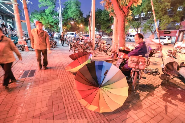 BEIJING, CHINA - CIRCA ARPIL 2014. Homem vende guarda-chuvas coloridos à noite na rua em Pequim, China por volta de abril 2014 . — Fotografia de Stock