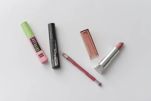 Maquillaje de artículos rímel, gel de frente, delineador de labios, lápiz labial en la mesa blanca . —  Fotos de Stock