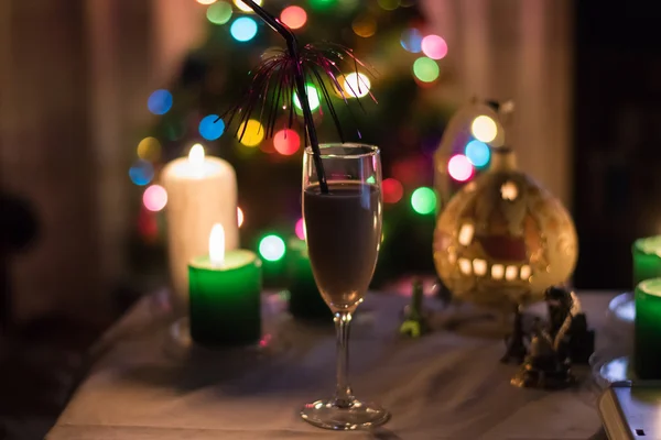 Moskou - Circa December 2015: een glas champagne op de tabel met kaarsen en feestelijk Nieuwjaar lampjes op de achtergrond in December 2015. — Stockfoto