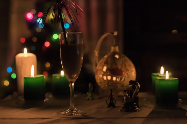 Moskou - Circa December 2015: een glas champagne op de tabel met kaarsen en feestelijk Nieuwjaar lampjes op de achtergrond in December 2015. — Stockfoto