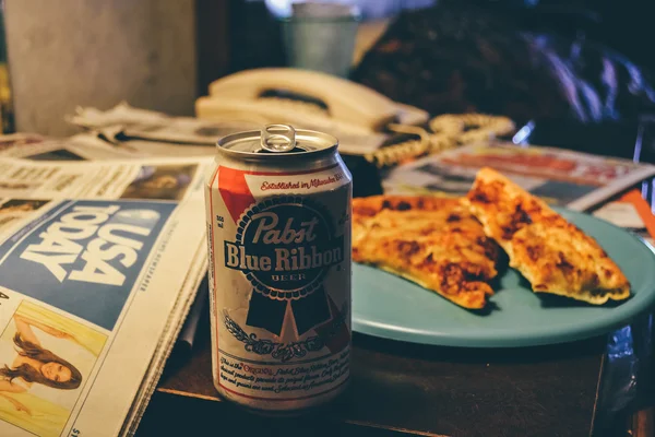 CINCINNATI, OH - CIRCA 2011: can beer and plate with pizza slices on the night table in a hotel suite in Cincinnati, OH, USA at summer 2011. — Stock Photo, Image