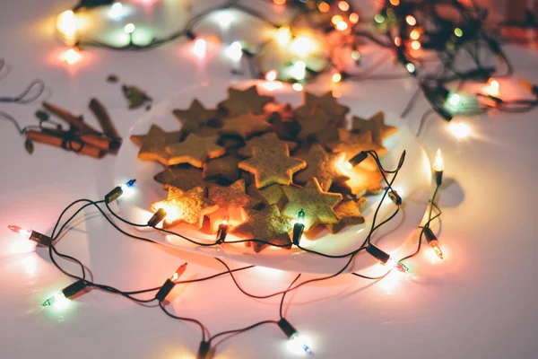 MOSCOU - 5 JANVIER 2016 : biscuits au gingembre de Noël en forme d'étoiles sur la table avec bâtons de cannelle et lumières festives la veille de Noël . — Photo