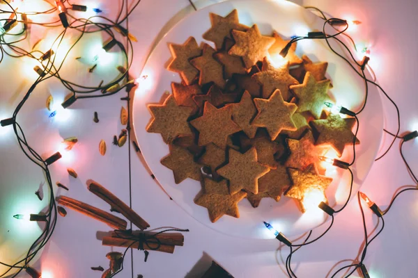 MOSCOU - 5 JANVIER 2016 : biscuits au gingembre de Noël en forme d'étoiles sur la table avec bâtons de cannelle et lumières festives la veille de Noël . — Photo