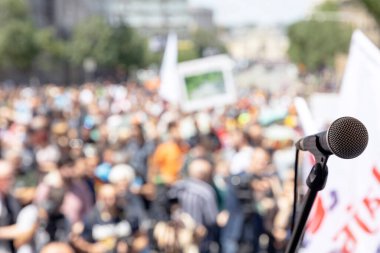 Mikrofona odaklan, arka planda kitlesel protestoda bulanık bir grup insan
