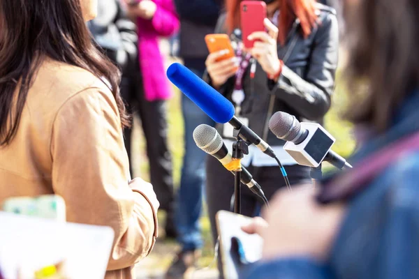 Press or news conference microphone in focus, mobile journalist filming media event with a smartphone