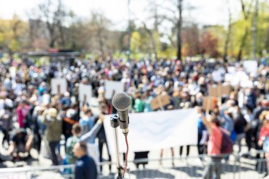 Protesto ya da halk gösterileri, mikrofona odaklanmak, arka planda bulanık bir grup insan