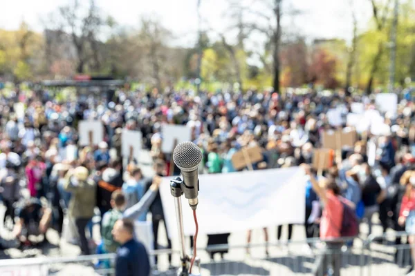 Protest or public demonstration, focus on microphone, blurred group of people in the background
